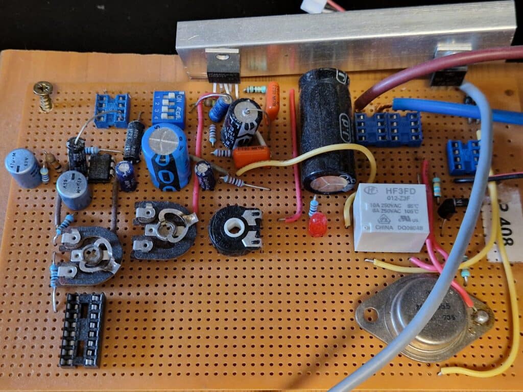 01 - Prototype 1 Nærbilde av et elektronisk kretskort med kondensatorer, motstander, reléer, kontakter og ledninger montert på et perforert prototypebrett.