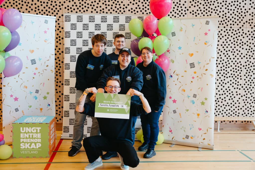 UE 2026 Fem personer poserer innendørs på et arrangement med fargerike ballonger og bannere, mens de holder et grønt og hvitt skilt med teksten